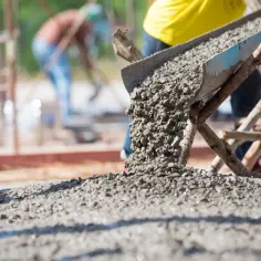 Beton wylewany z rynny na placu budowy. Aby obliczyć metry sześcienne betonu, zmierz długość, szerokość i wysokość formy.