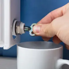 Dłoń z kluczykiem przy grzejniku aluminiowym, przygotowanie do skręcania.