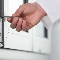 Dłoń używa klucza do regulacji okien, precyzyjnie dopasowując zawias.