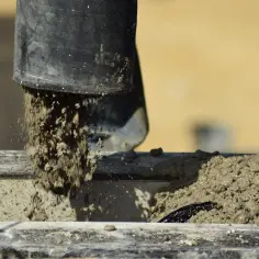 Z czarnej rury leje się mokry beton, tworząc nową strukturę. To właśnie beton, budulec naszych czasów.