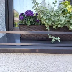 Rozporowa barierka na parapet z koszem pełnym fioletowych i żółtych kwiatów.