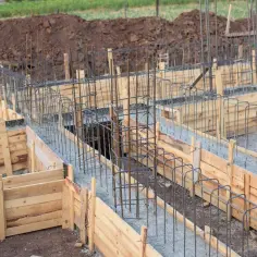 Szalowanie ław fundamentowych zbrojonych stalą, gotowe do zalania betonem. Budowa nabiera kształtów.