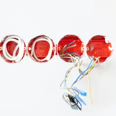 Cztery puszki instalacyjne z przewodami elektrycznymi, gotowe do podłączenia zgodnie z normą.
