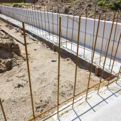 Budowa fundamentów: pionowe i poziome pręty na zbrojenie schodów, gotowe do zalania betonem.