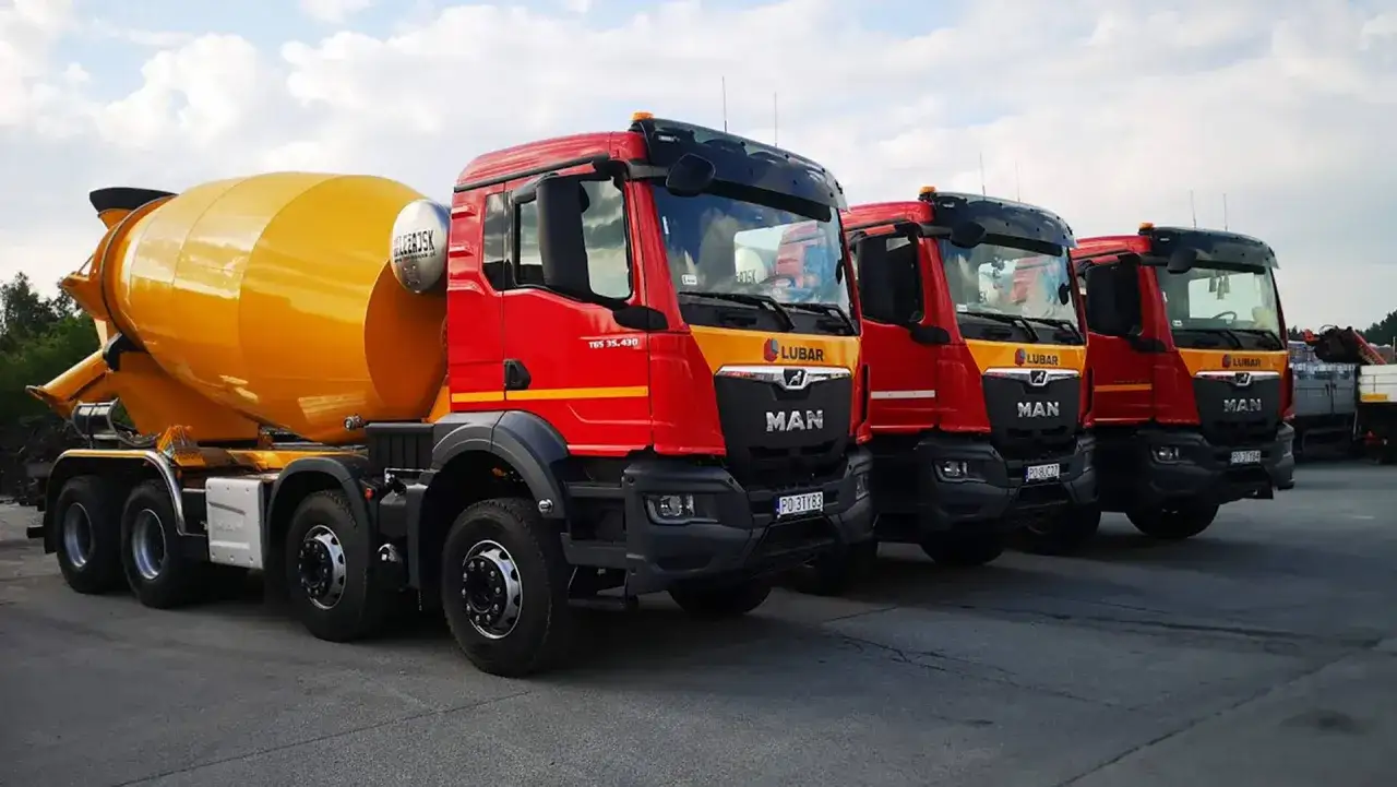 Czerwone gruszki betonu marki MAN stoją w rzędzie. Zastanawiasz się, ile kosztuje gruszka betonu? Te potężne maszyny to klucz do budowy.