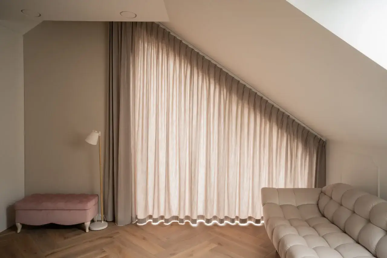 Eleganckie karnisze sufitowe aranżacje tworzą przytulną atmosferę. Jasne zasłony i wygodna sofa zapraszają do relaksu.